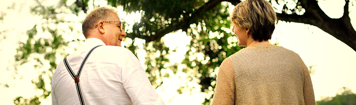 close-up of elderly couple holding hands and smiling at one another