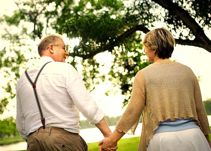 elderly couple holding hands as they're walking away