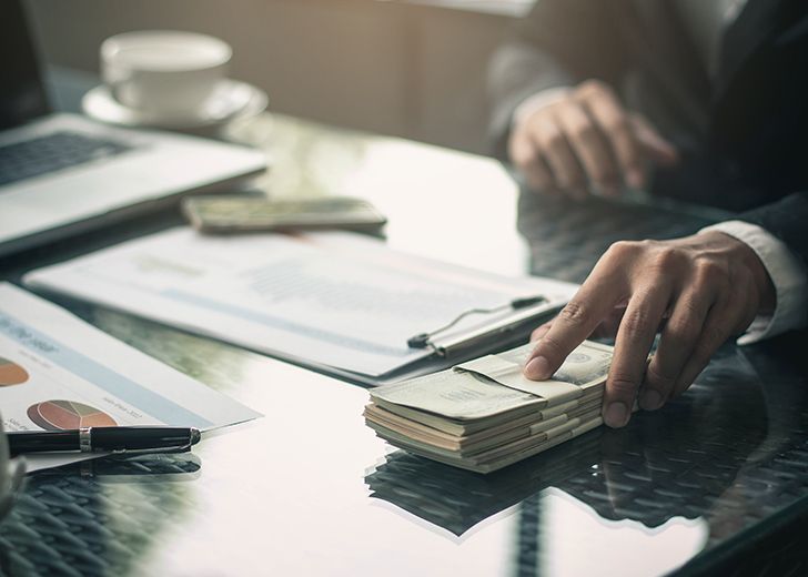 gentleman passing a stack of money on his desk