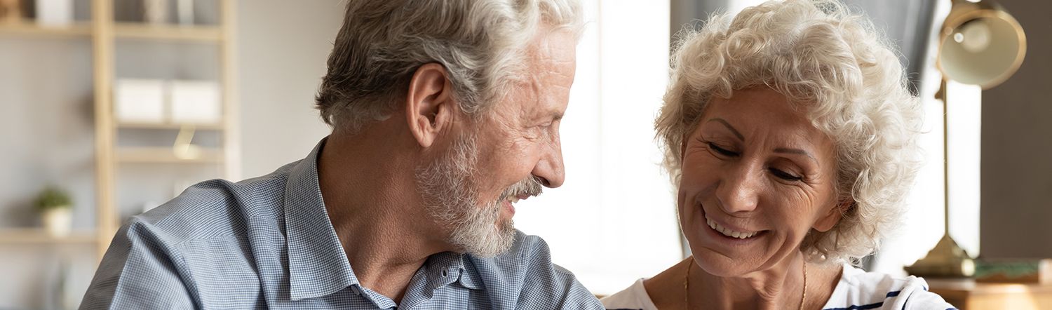 elderly couple smiling at one another