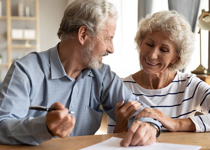 close-up of elderly couple smiling at one another and filling out information