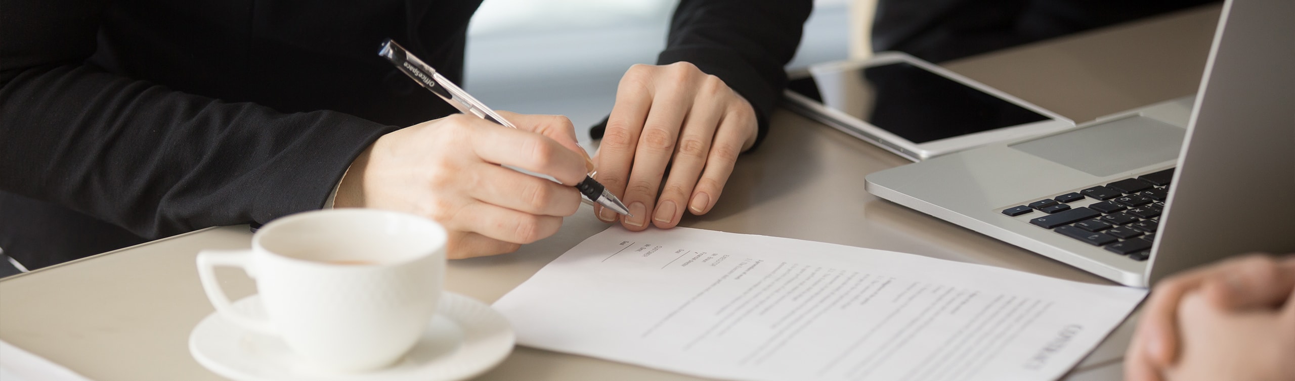 close up of woman signing a document to designate beneficiary