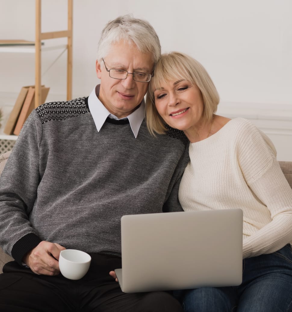 elderly couple smiling and looking at information on computer