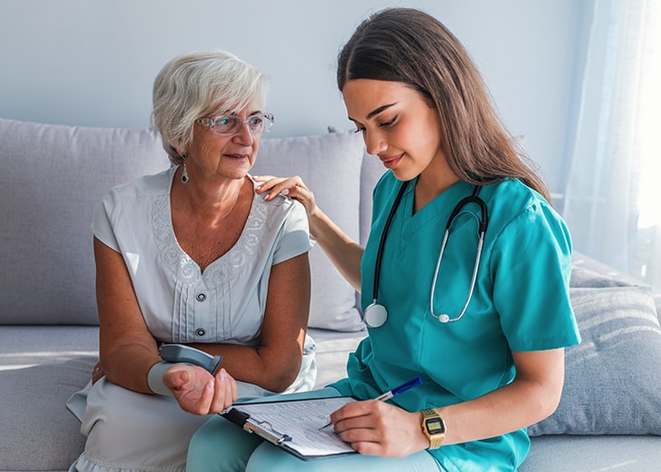 close-up of at home nurse touching elderly woman shoulder