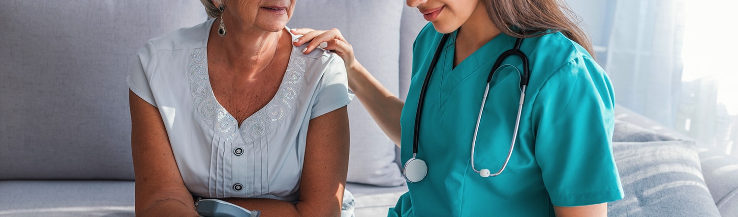 at home nurse touching elderly woman shoulder