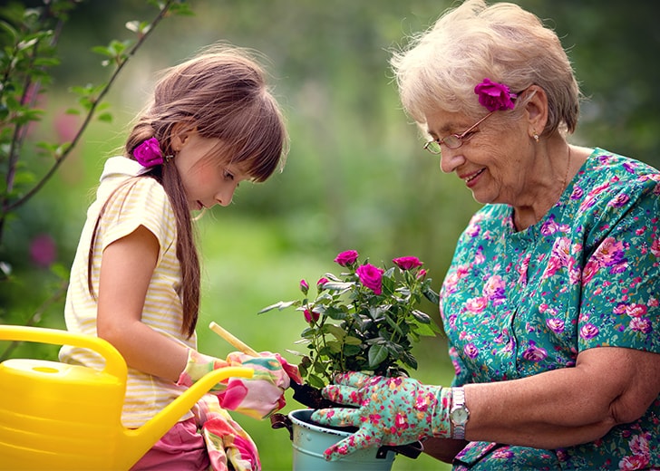 grandma planting flowers with granddaughter