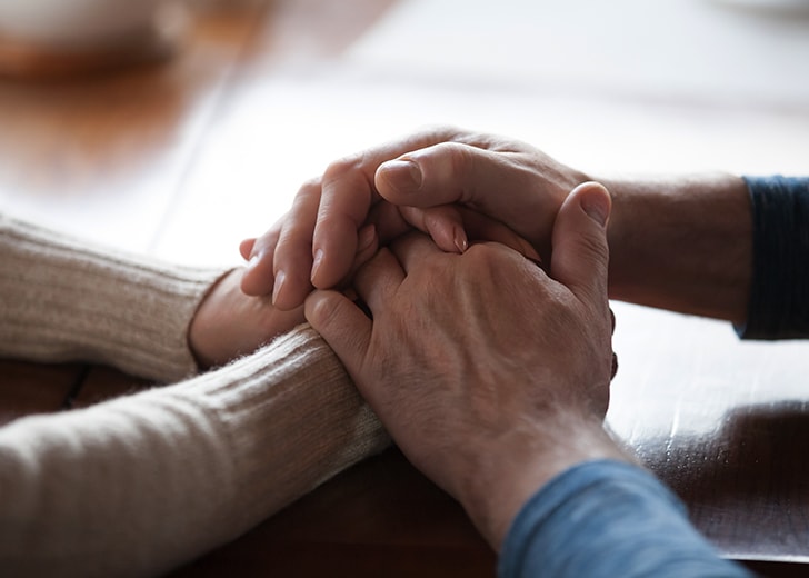 close-up of two elderly people holding hands