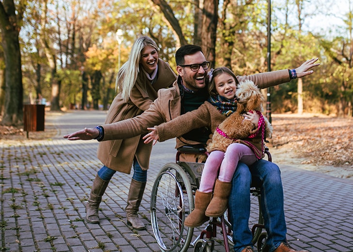 close-up of wife pushing husband in wheelchair with their daughter