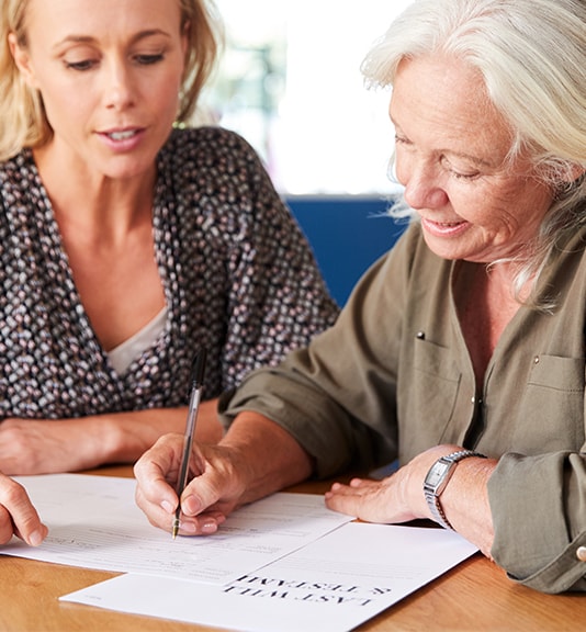 elderly woman signing form with woman