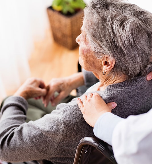 nurse putting her hand on elderly woman shoulder