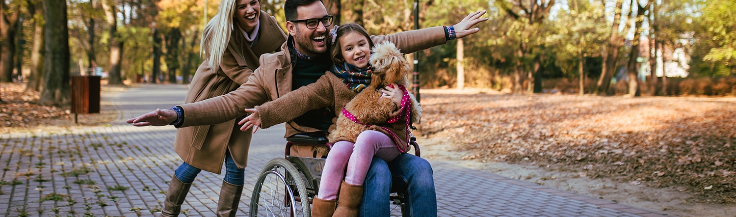 wife pushing husband in wheelchair with their daughter