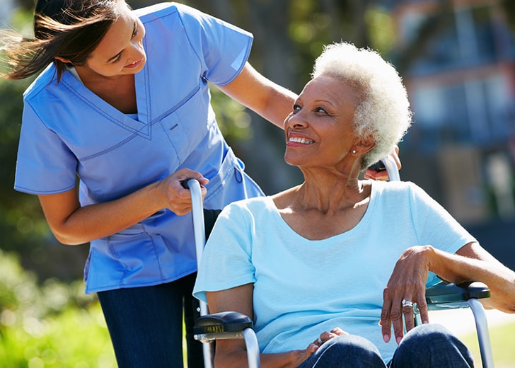 close-up of nurse pushing elderly woman around in wheelchair