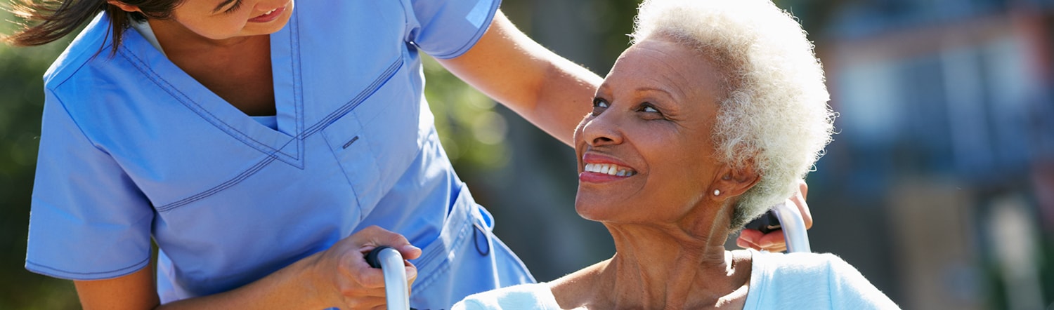 nurse pushing elderly woman around in wheelchair