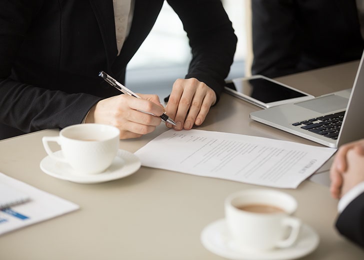 close up of woman signing a document to designate beneficiary